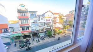 A street view with buildings, a coffee shop, and parked motorcycles. - TTR Vincent Hotel (Xuan Huong - Da Lat)