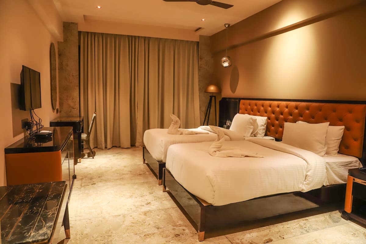A hotel room with a large bed, a desk, a television, and a ceiling fan.