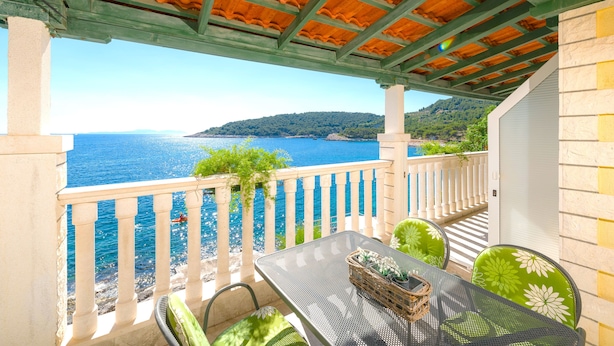 Un balcon avec une table et des chaises, offrant une vue sur la côte.