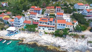 Une zone résidentielle côtière avec des immeubles à plusieurs étages, un littoral rocheux et des eaux turquoise cristallines.
