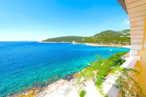 A coastal view with clear blue sea, a sandy beach, and a mountainous backdrop. - Apartments Mario Tudor (Hvar)
