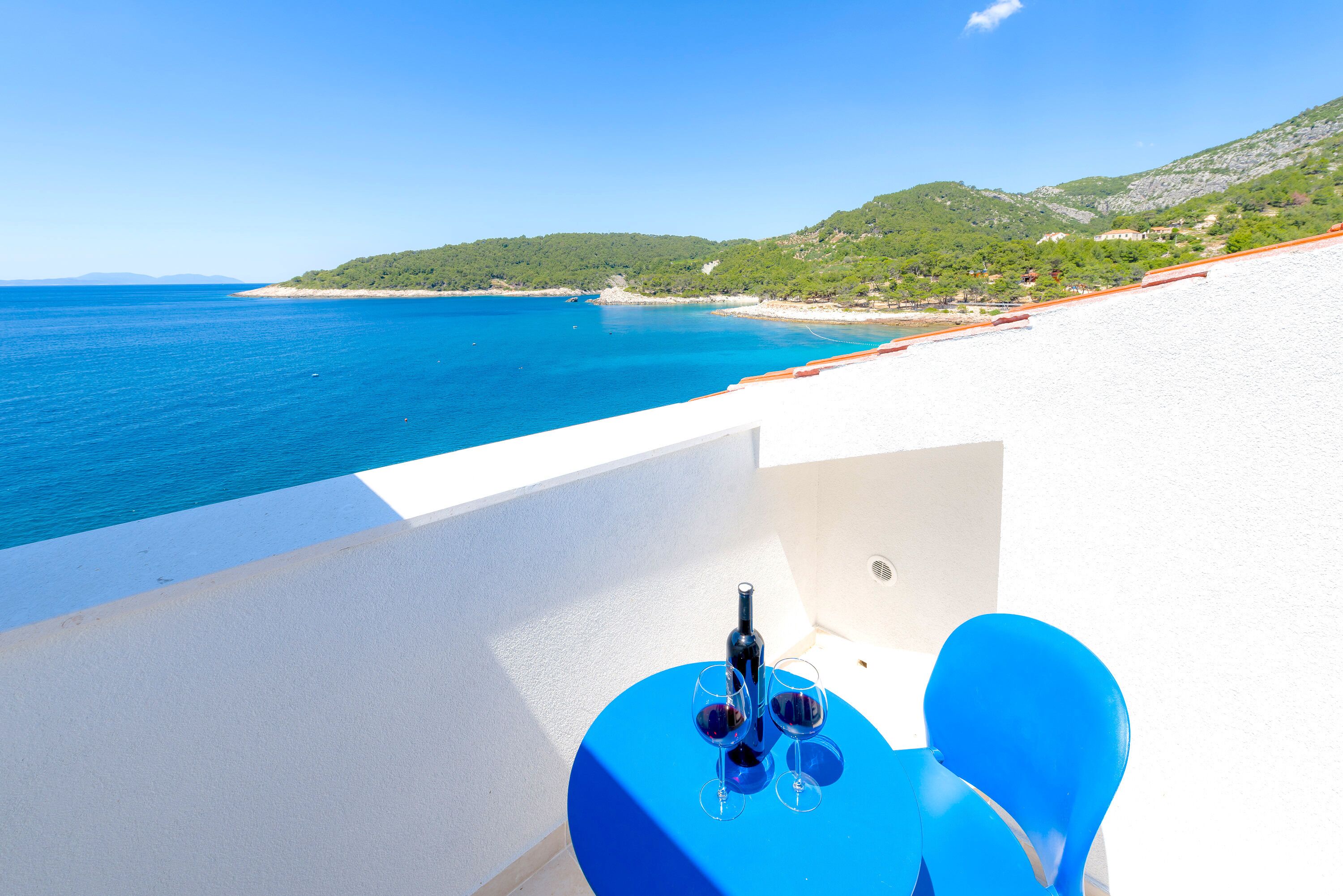 Un balcone con tavolo e sedie affacciato su una spiaggia e il mare.