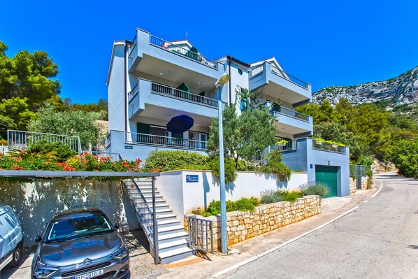 A modern two-story building with balconies, a staircase, and a stone wall.