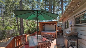 A covered outdoor patio with a table and chairs, a grill, and a spa hours sign.