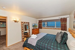 Un dormitorio con cama, cómoda, espejo y ventana con cortinas.