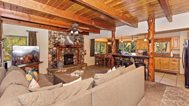 A cozy living room with a stone fireplace, a television, and a sofa.