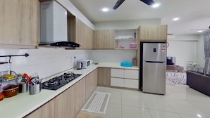 A modern kitchen with a gas stove, microwave, and stainless steel refrigerator. - Alyssa Dwiputra Homestay (Putrajaya)