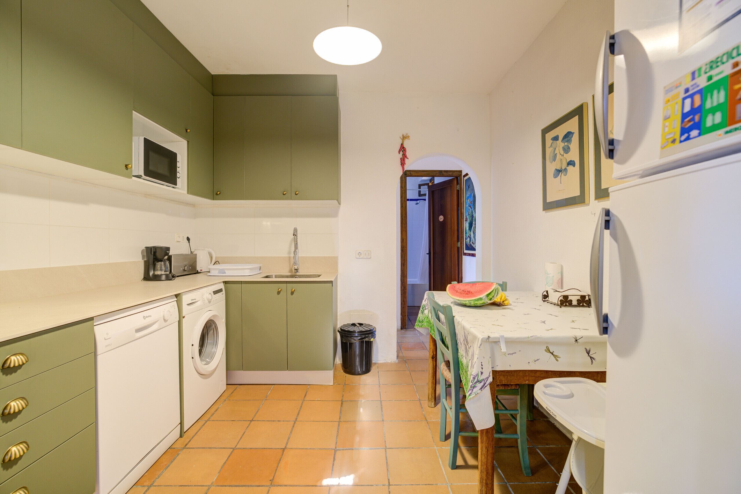 A compact kitchen with a washing machine, microwave, and a dining area with a table and chairs.