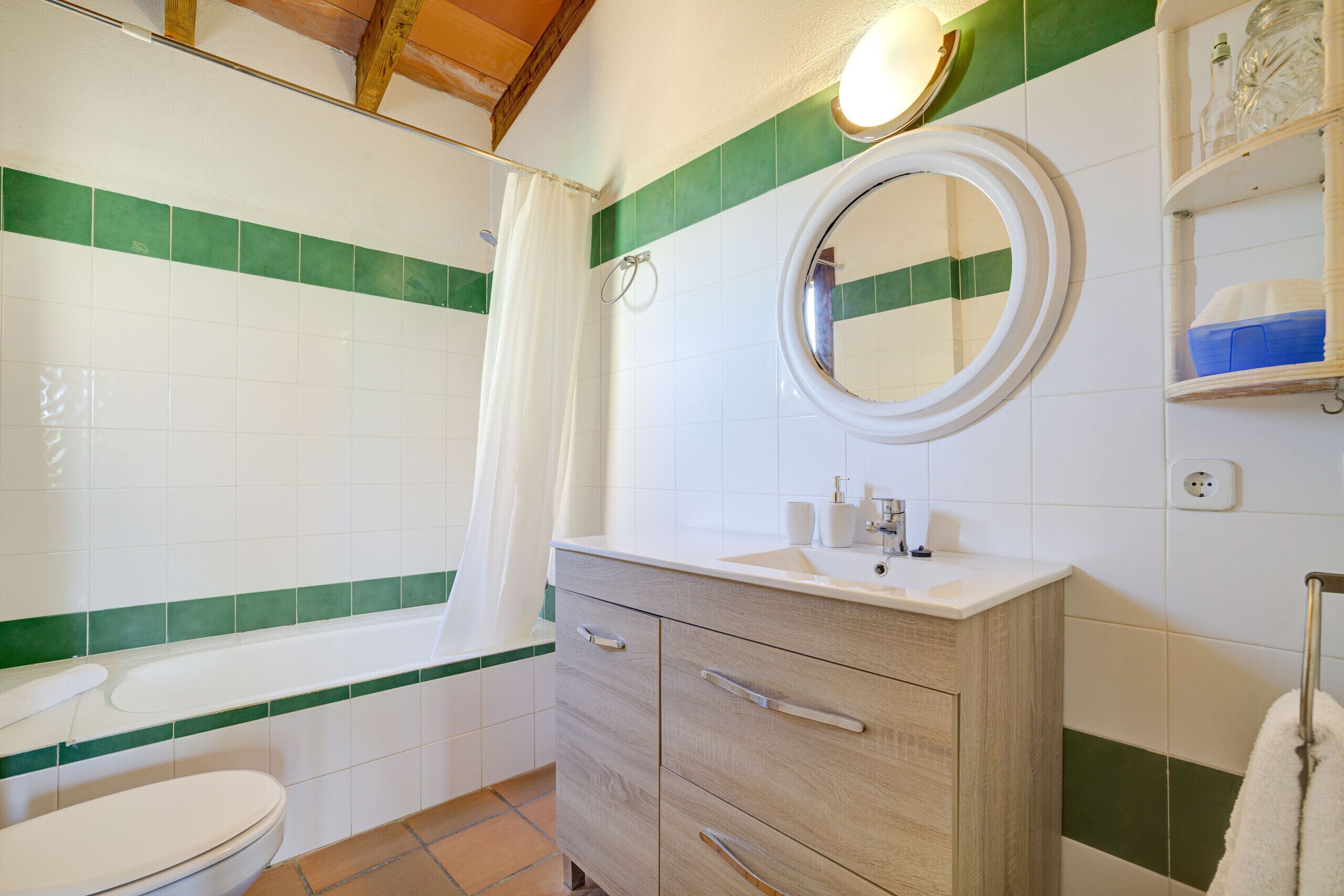 A bathroom with a toilet, a sink, a mirror, and a shower curtain.