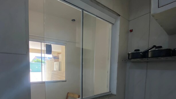 A kitchen with a window, a sink, and a shelf with pots.