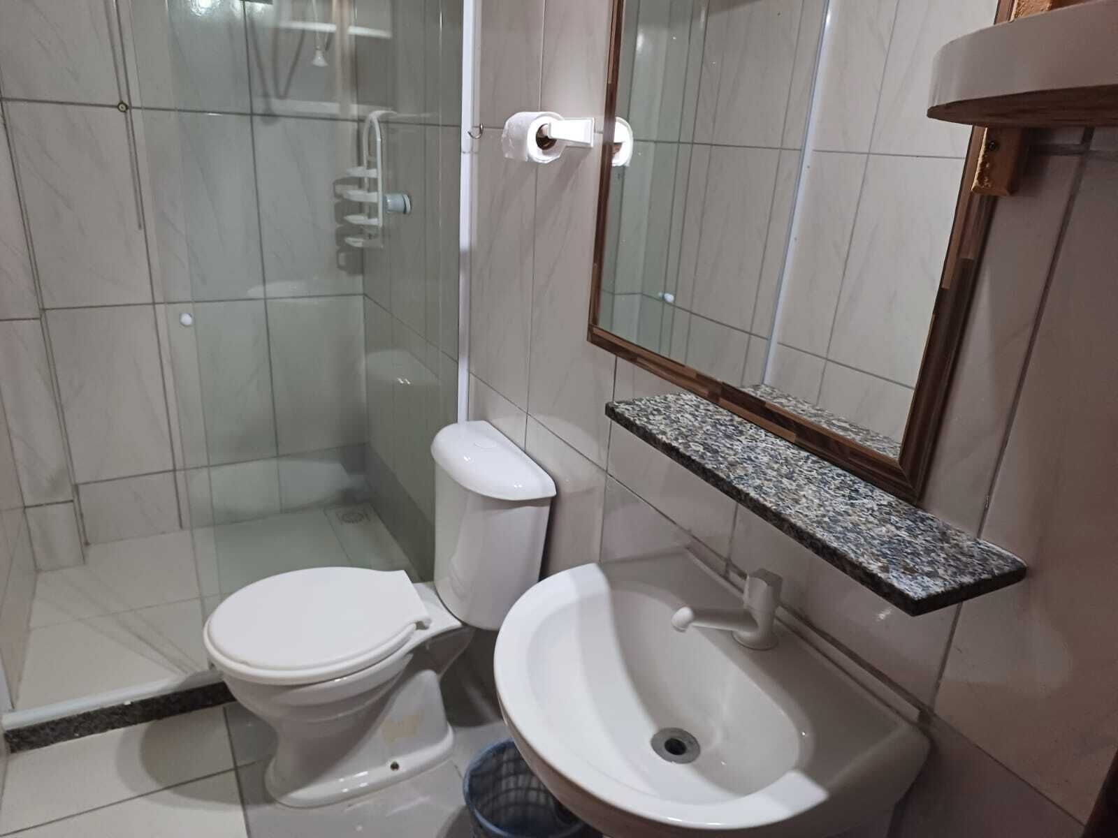 Une salle de bain équipée de toilettes, d’un lavabo et d’une douche à parois en verre.