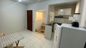 A compact kitchen with a dining table, a refrigerator, and a blender.