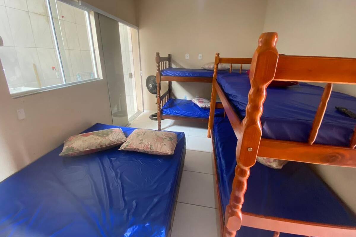 Une chambre de dortoir avec des lits superposés, une fenêtre et un ventilateur.