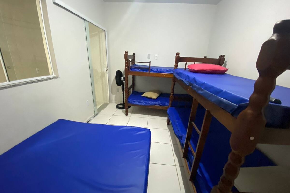 Une chambre de dortoir avec des lits superposés, un ventilateur et une fenêtre.