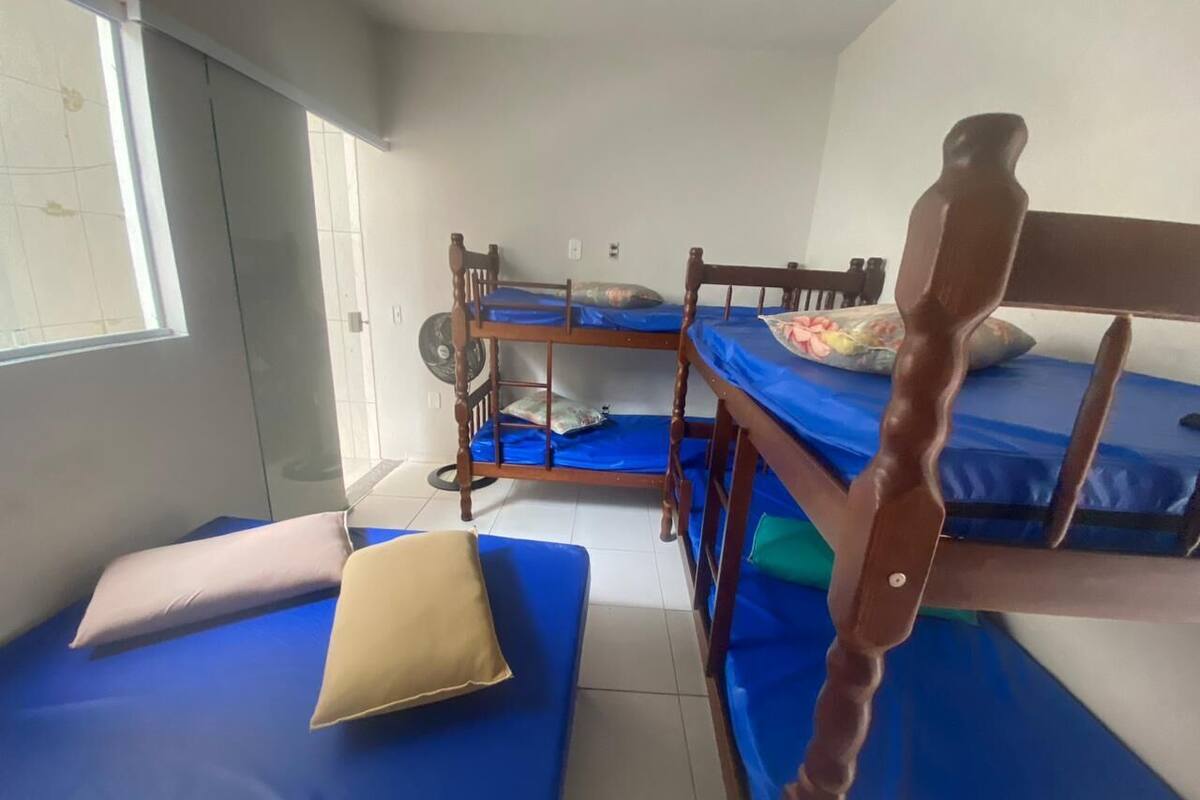 Une chambre de dortoir avec des lits superposés, une fenêtre et un ventilateur.