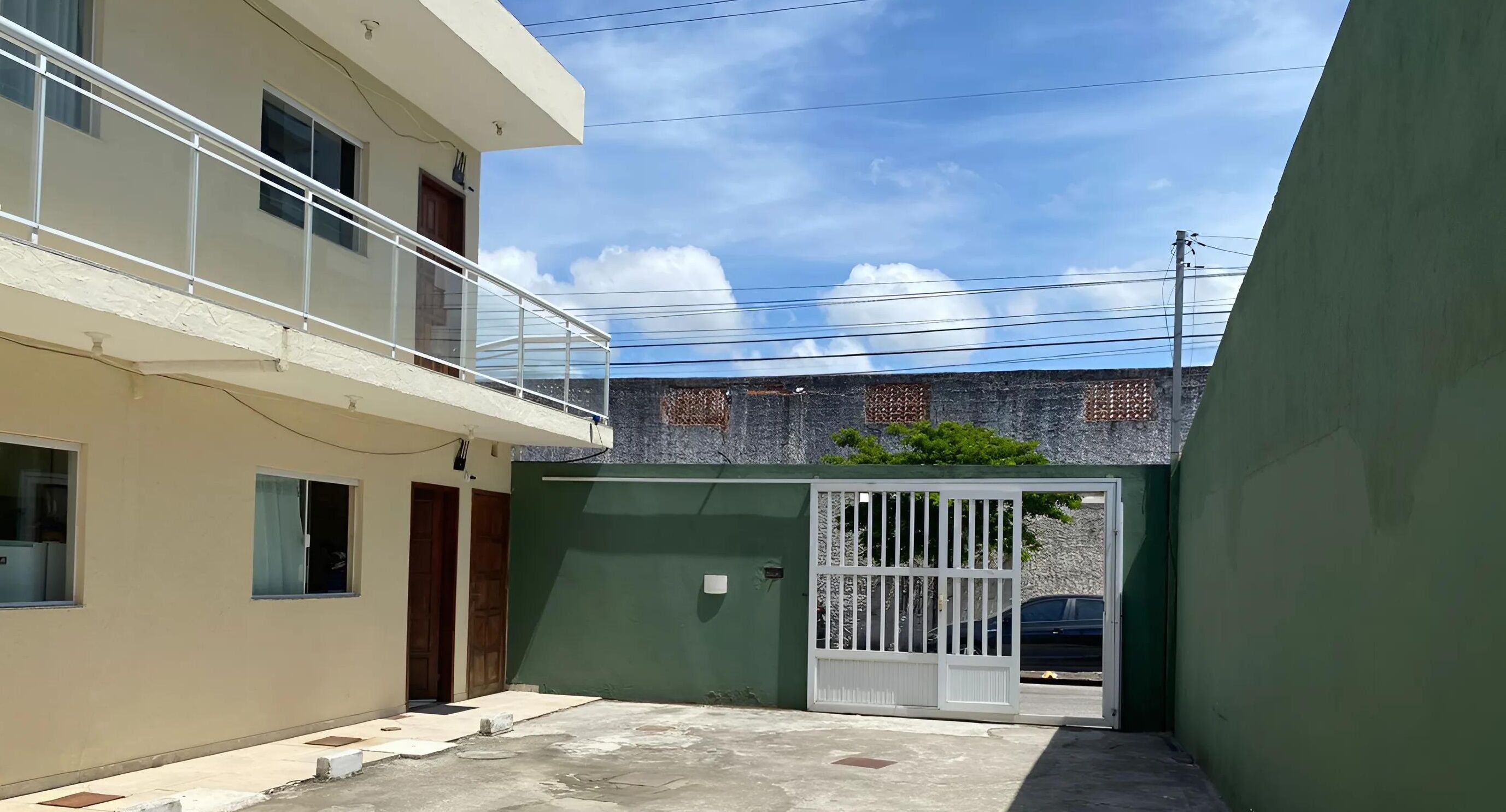 A residential building with a gated entrance, a balcony, and a clear sky.