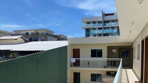 A multi-story building with balconies, a covered outdoor area, and a clear sky.