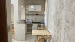 A compact kitchen with a microwave, cabinets, and a wooden table.