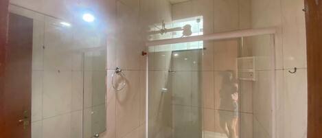 A bathroom with a glass-enclosed shower, a toilet, and a mirror.