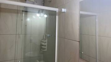 A modern bathroom with a glass shower enclosure, a white towel rack, and a visible toilet.