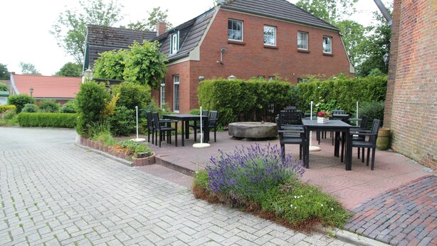 Tiilitalo, jossa on kivetty patio, ulkotila istumiseen ja puutarha, jossa kasvaa laventelia.