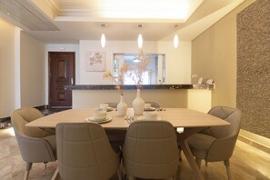 Un comedor con una mesa rectangular, seis sillas y dos jarrones con flores secas.