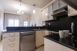 Una cocina moderna con lavavajillas, pileta doble y encimera negra.