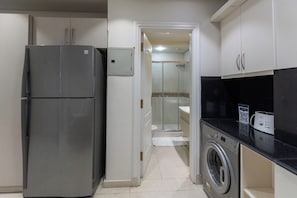 A compact kitchen with a refrigerator, washing machine, and a microwave. - El Safwa Resort (New Cairo)