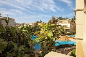 Una piscina rodeada de exuberante vegetación tropical, con un cielo azul despejado.