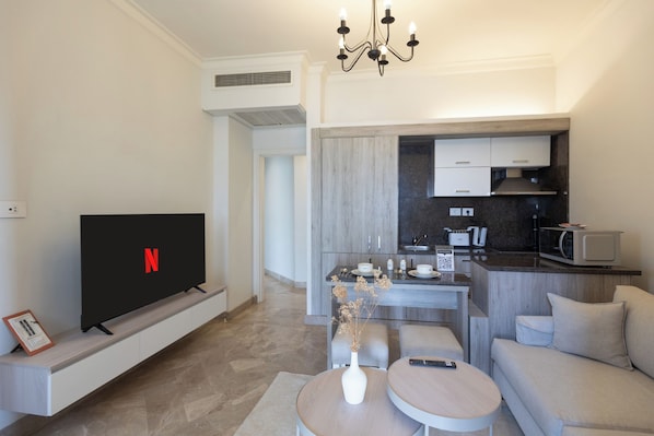 Una sala de estar moderna con una televisión de pantalla plana, un comedor y una kitchenette.