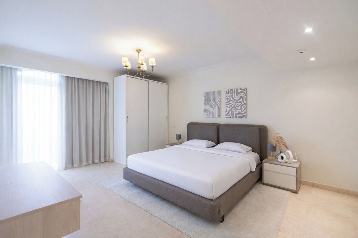 Un dormitorio moderno con una cama grande, un armario, una mesita de noche y vistas al exterior.