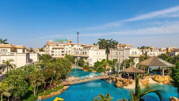 Un resort con piscina, palmeras y un puente.
