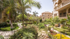 Un patio con palmeras, un camino de piedra y abundante vegetación.