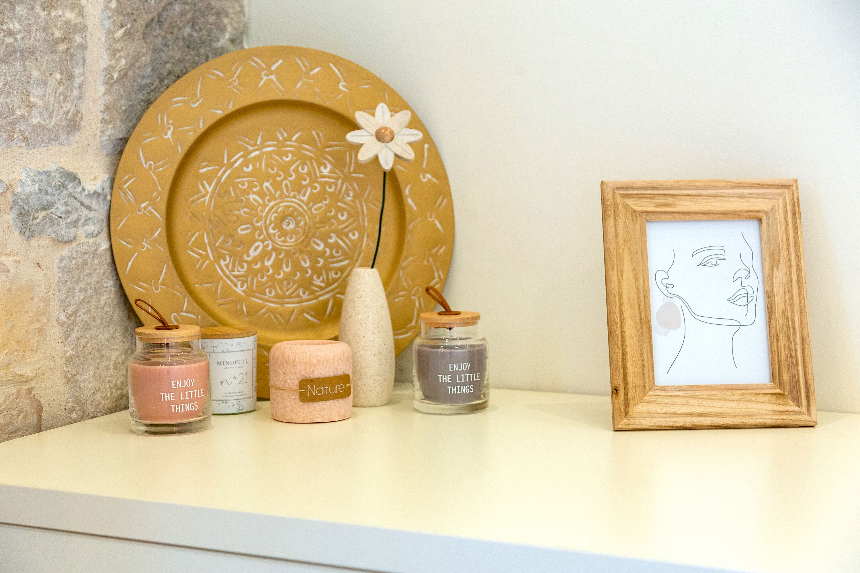 A shelf with decorative items including a mandala plate, candles, and a framed drawing.