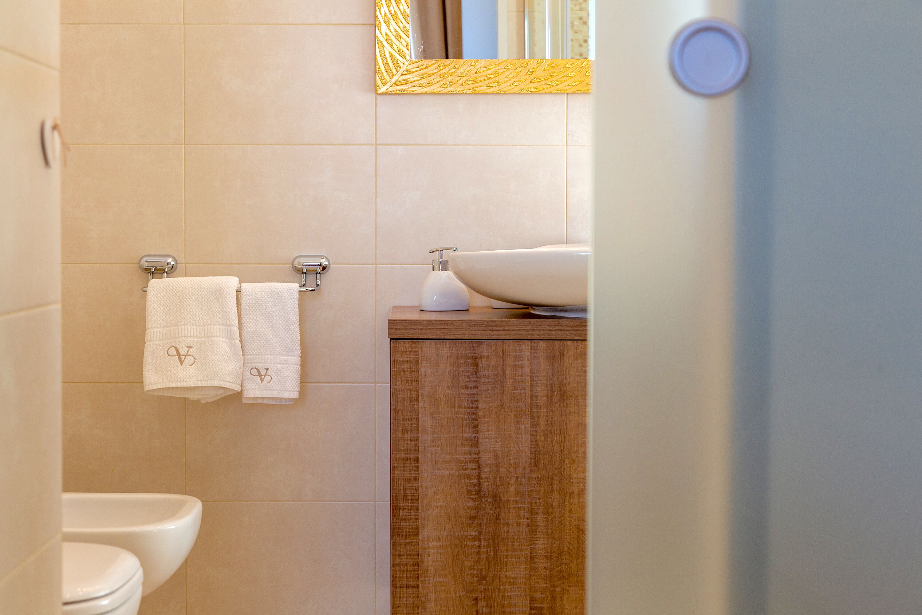 Ein Badezimmer mit Toilette, Waschbecken mit Spiegel darüber und zwei Handtüchern an einem Handtuchhalter.