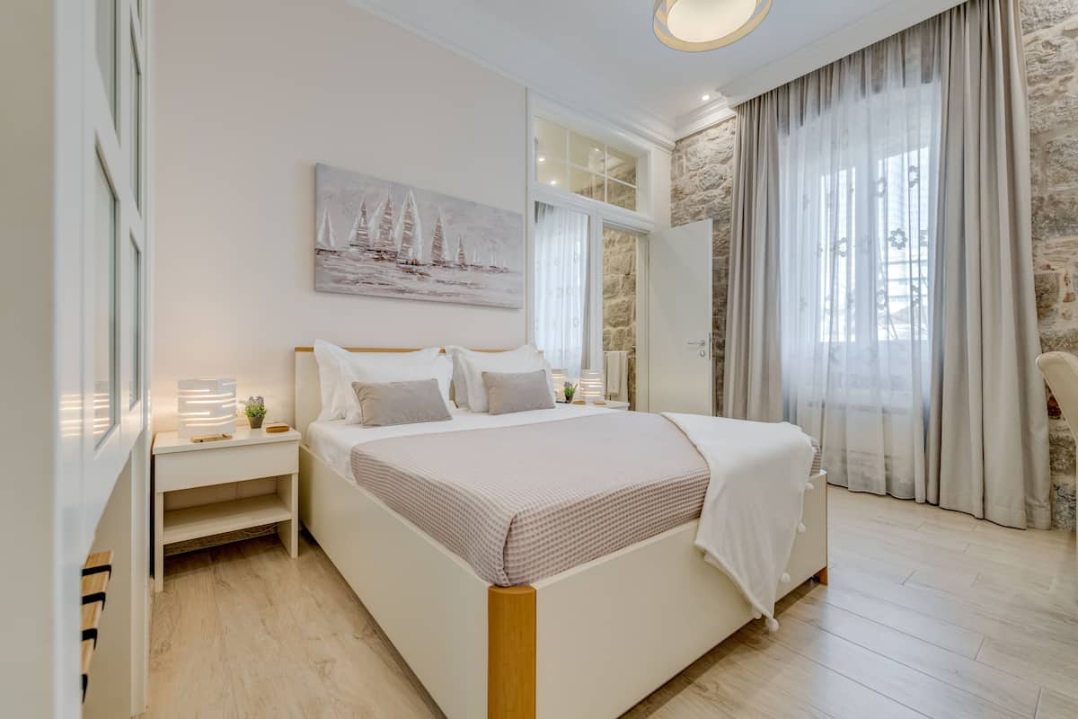 Un dormitorio moderno con una cama grande, una mesita de noche y un cuadro de veleros en la pared.