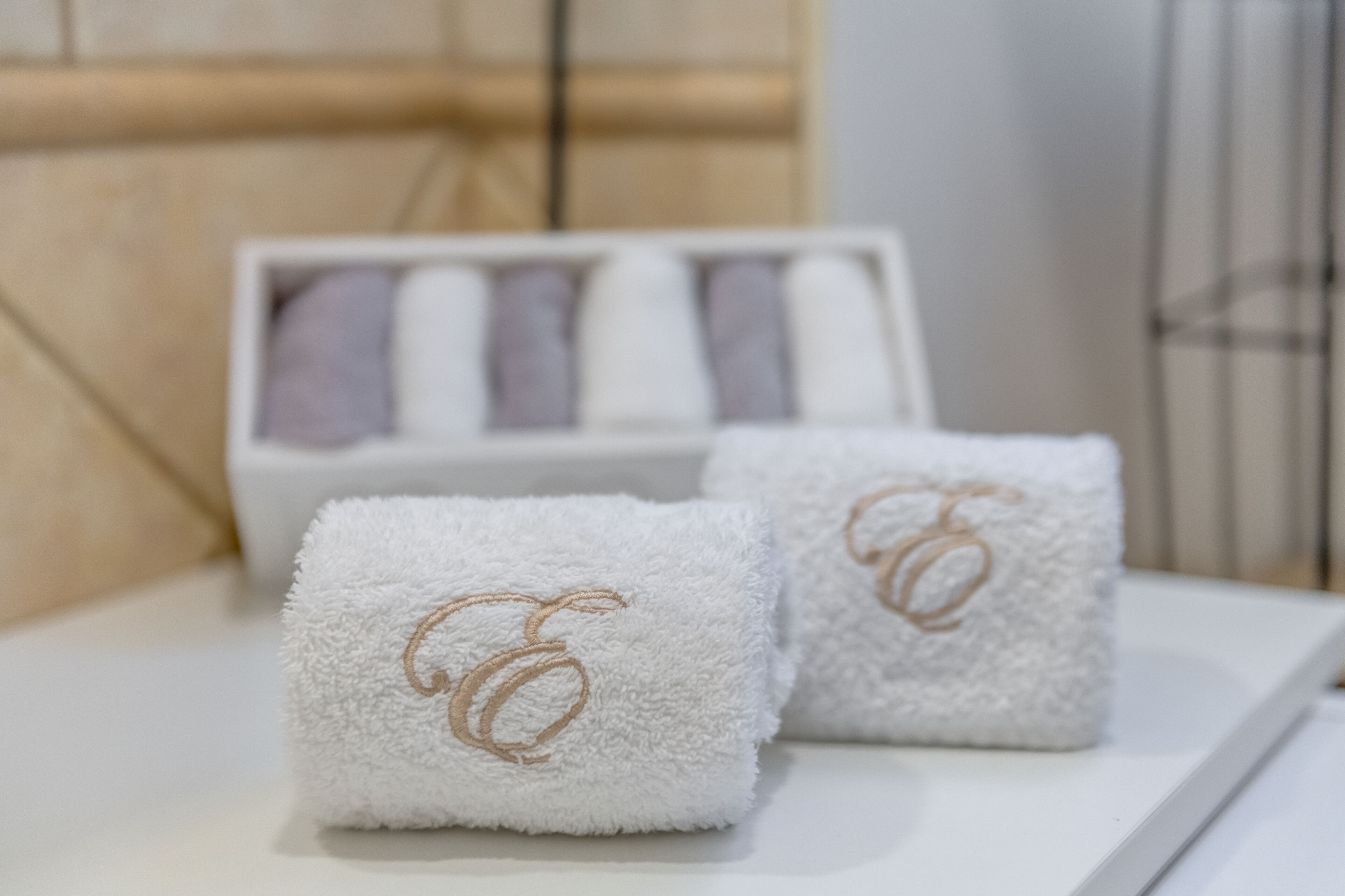 Two white towels with a gold emblem on a white tray.