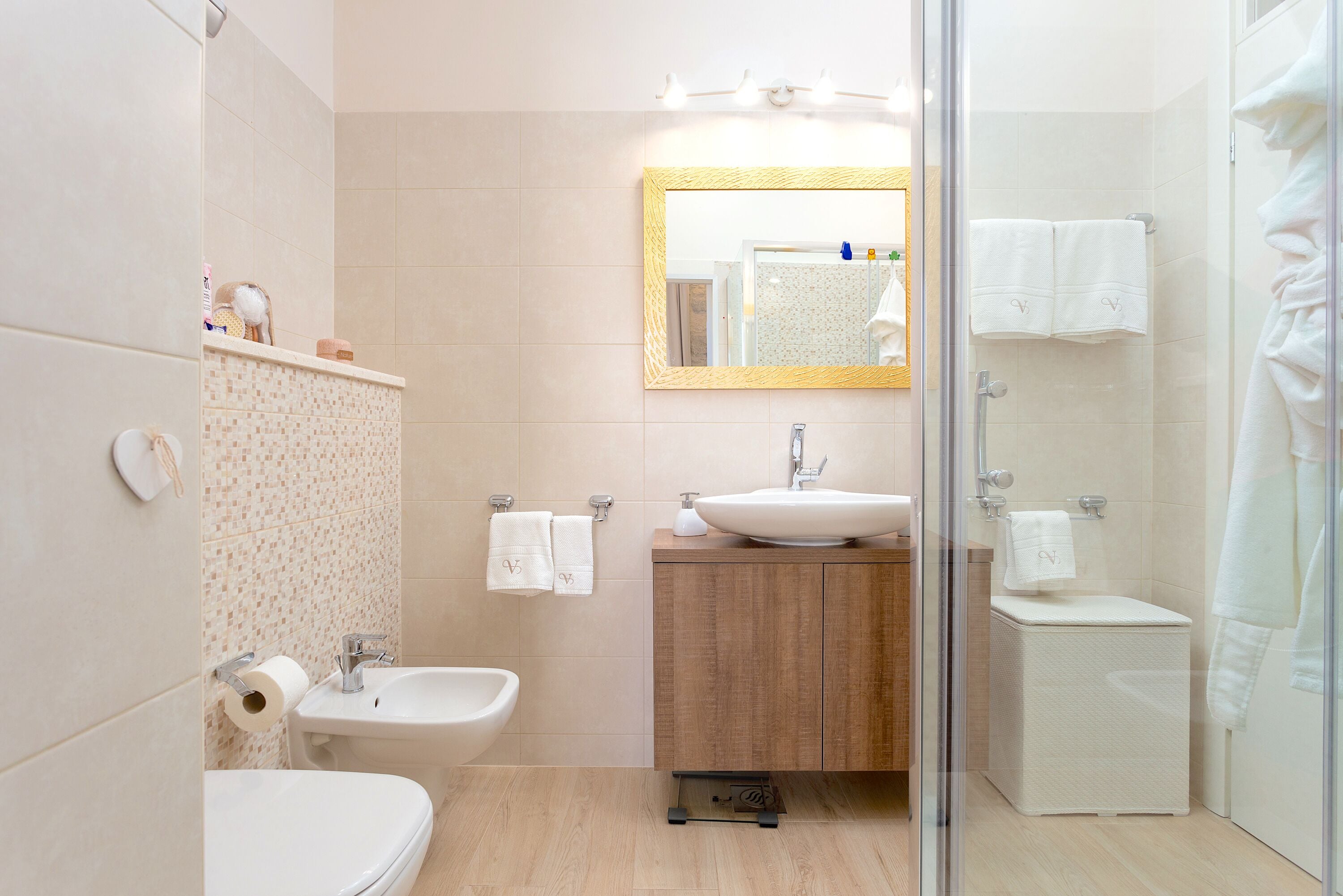 A modern bathroom with a toilet, bidet, sink, and a glass-enclosed shower area.