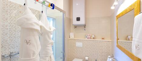 A bathroom with a glass shower enclosure, a toilet, a sink, and a mirror with a gold frame.