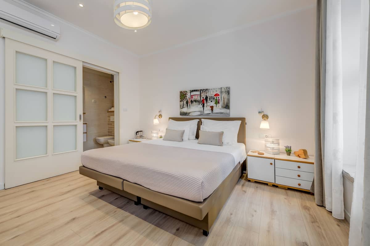 Un dormitorio moderno con una cama grande, una mesita de noche con lámpara, un cuadro en la pared y un armario.