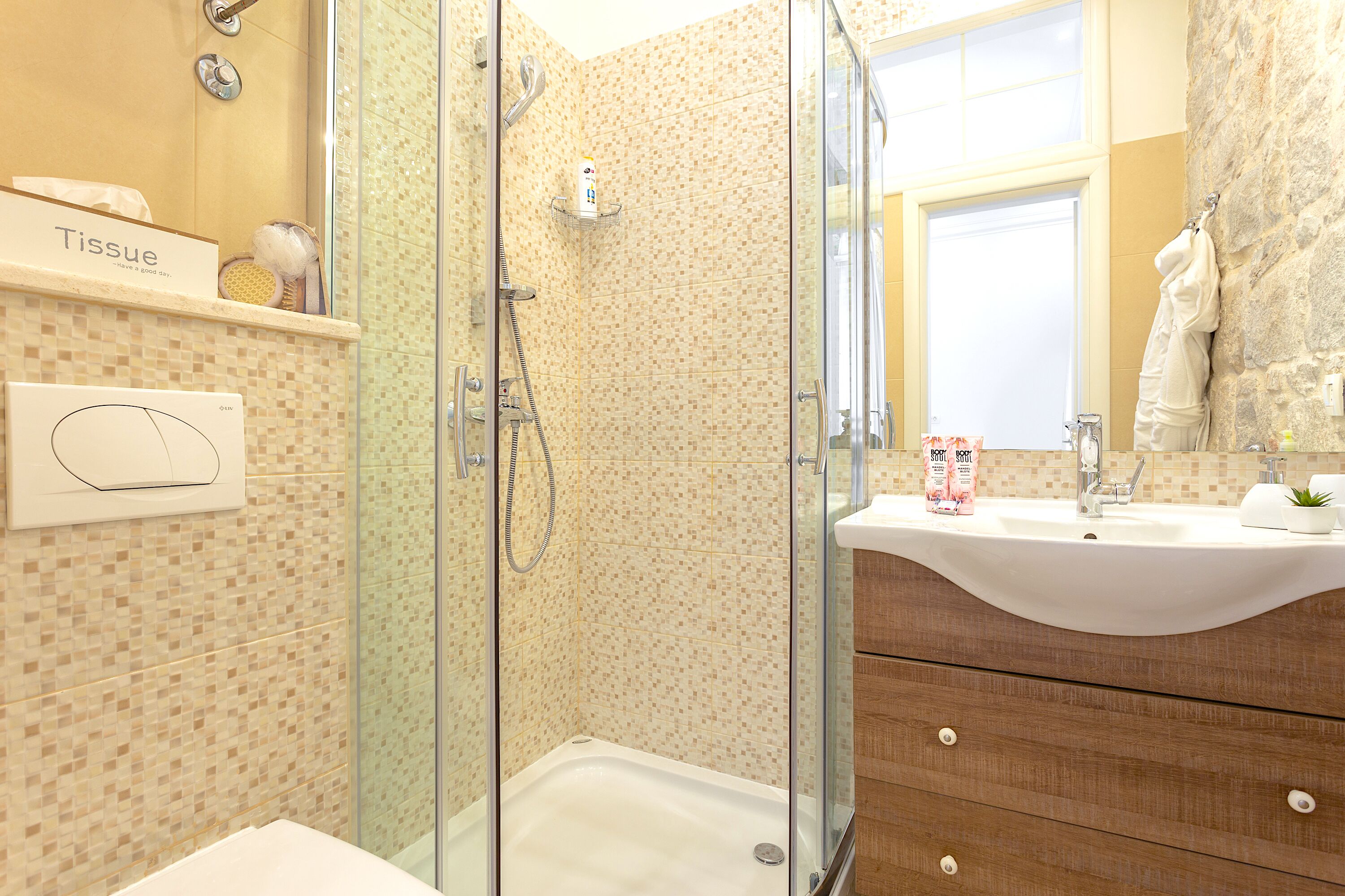 Ein modernes Badezimmer mit einer gläsernen Duschkabine, einem weißen Waschbecken und einem Holz-Waschtisch.