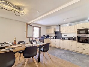 Cozinha moderna com armários de madeira, uma mesa de jantar com cadeiras e uma janela grande que ilumina naturalmente o espaço.