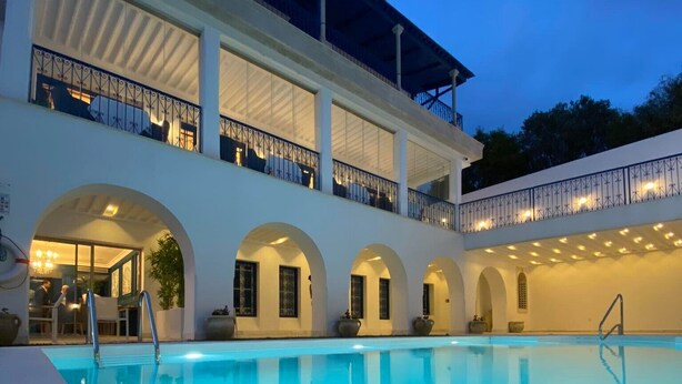 Una piscina con un edificio blanco al fondo.