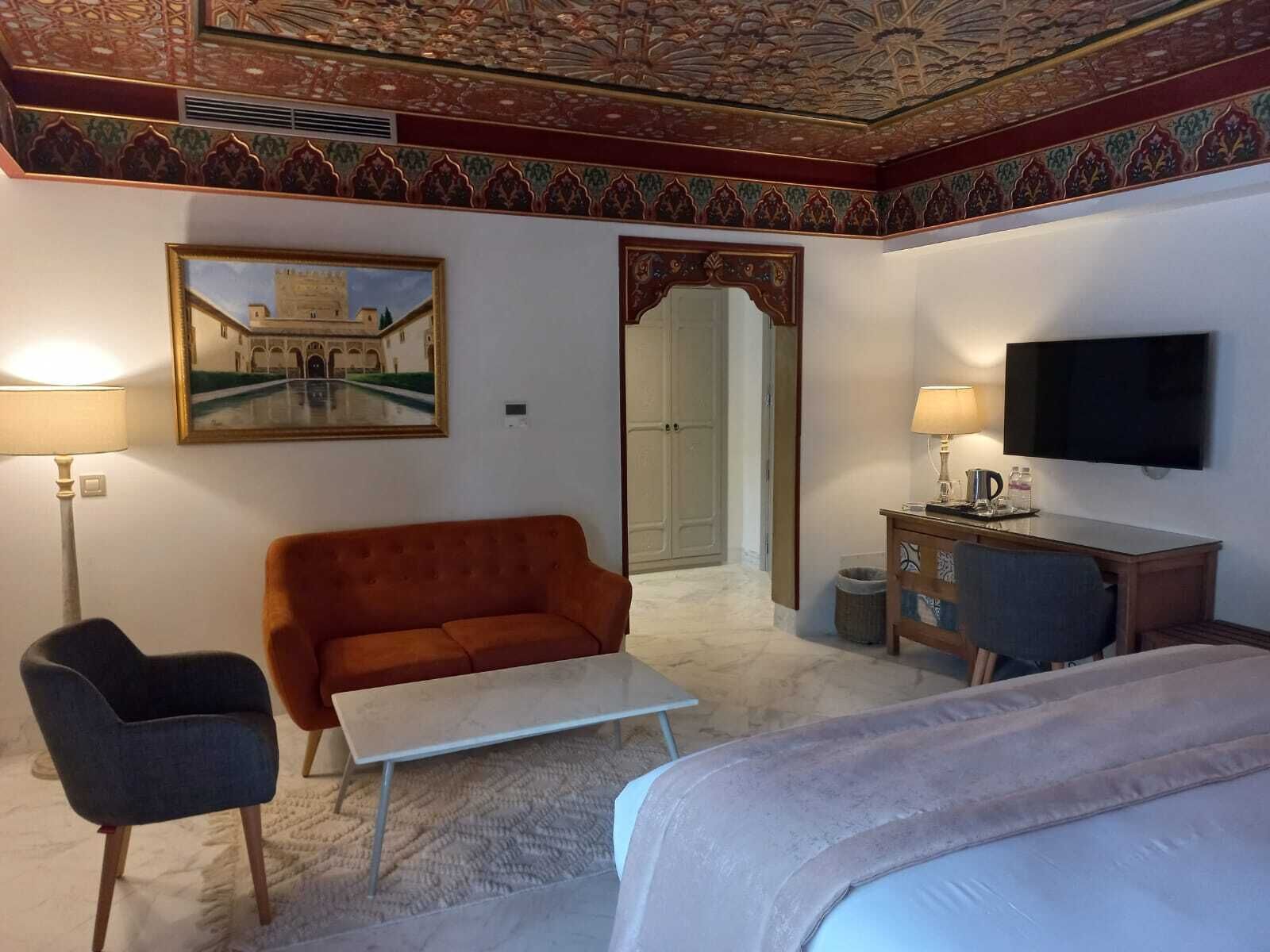 Una habitación de hotel con una cama, un sofá, un escritorio, un televisor y un cuadro de un edificio.