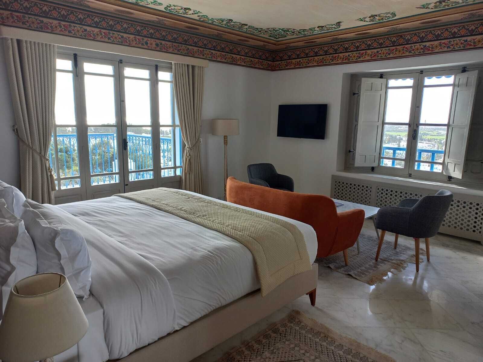 A hotel room with a bed, a desk, a chair, and a TV.
