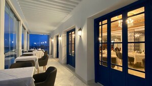 Un pasillo con mesas y sillas, vista del cielo nocturno y un comedor con paredes azules y candelabros.