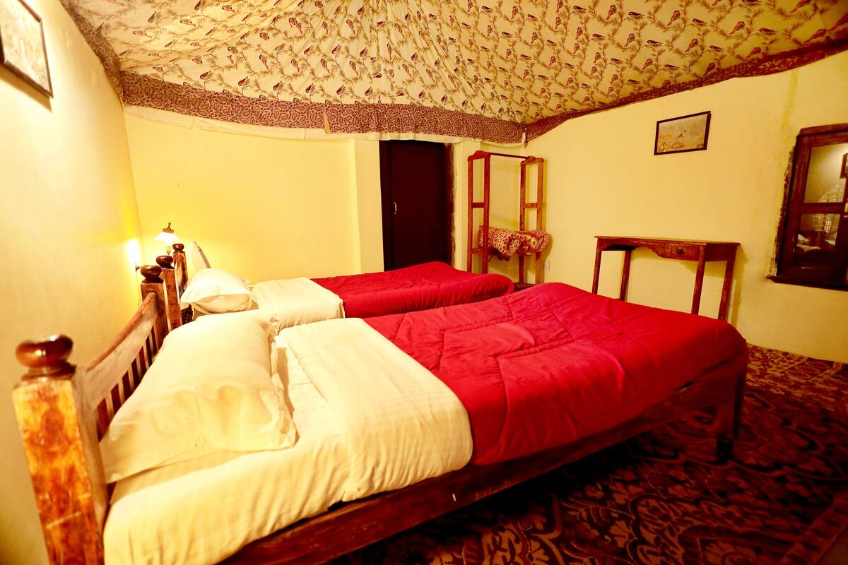 A room with two beds, a wooden headboard, a mirror, and a patterned carpet.