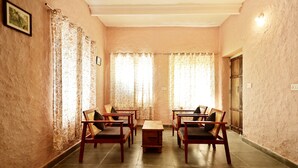 A room with four wooden chairs and a small table, with curtains on the windows.