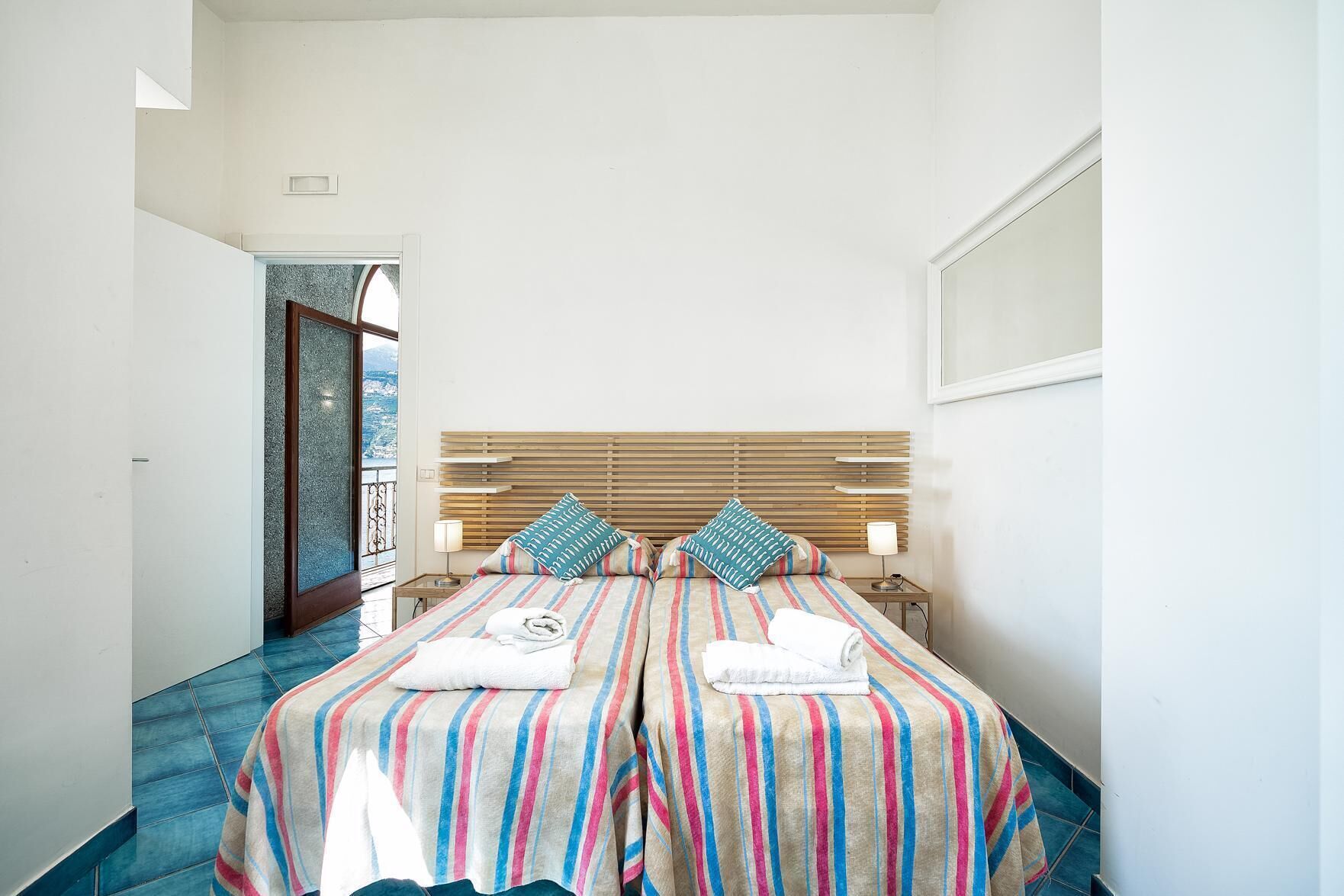 Une chambre d’hôtel avec un grand lit, deux tables de chevet et une vue sur la ville par la fenêtre.
