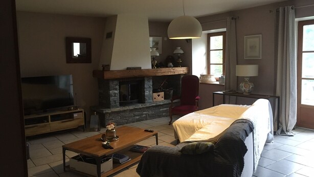 A living room with a fireplace, a sofa, a TV, and a dining table. - Beautiful building at the foot of the mountains, 15kms from Lake Annecy,  (Ugine)